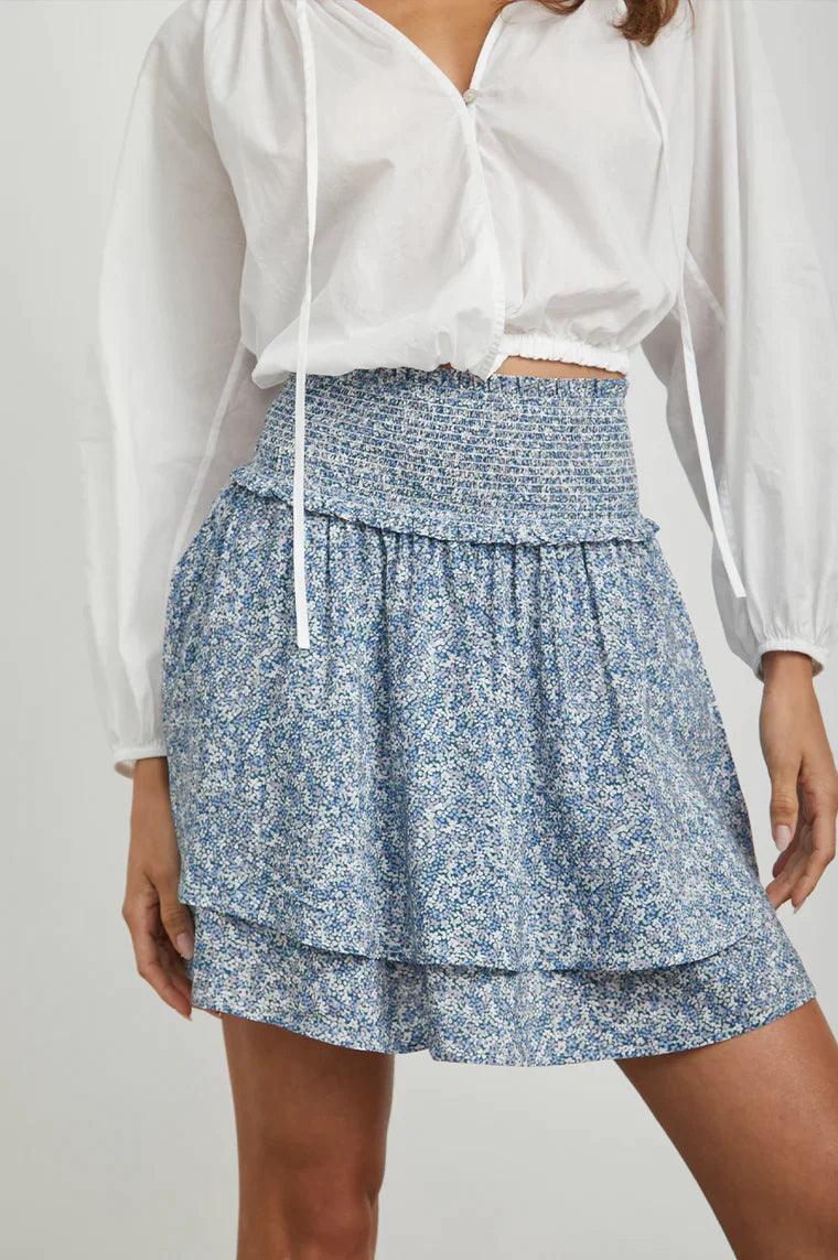 Kvinne med blå blomstrete miniskjørt og hvit bluse, sommermote for dame