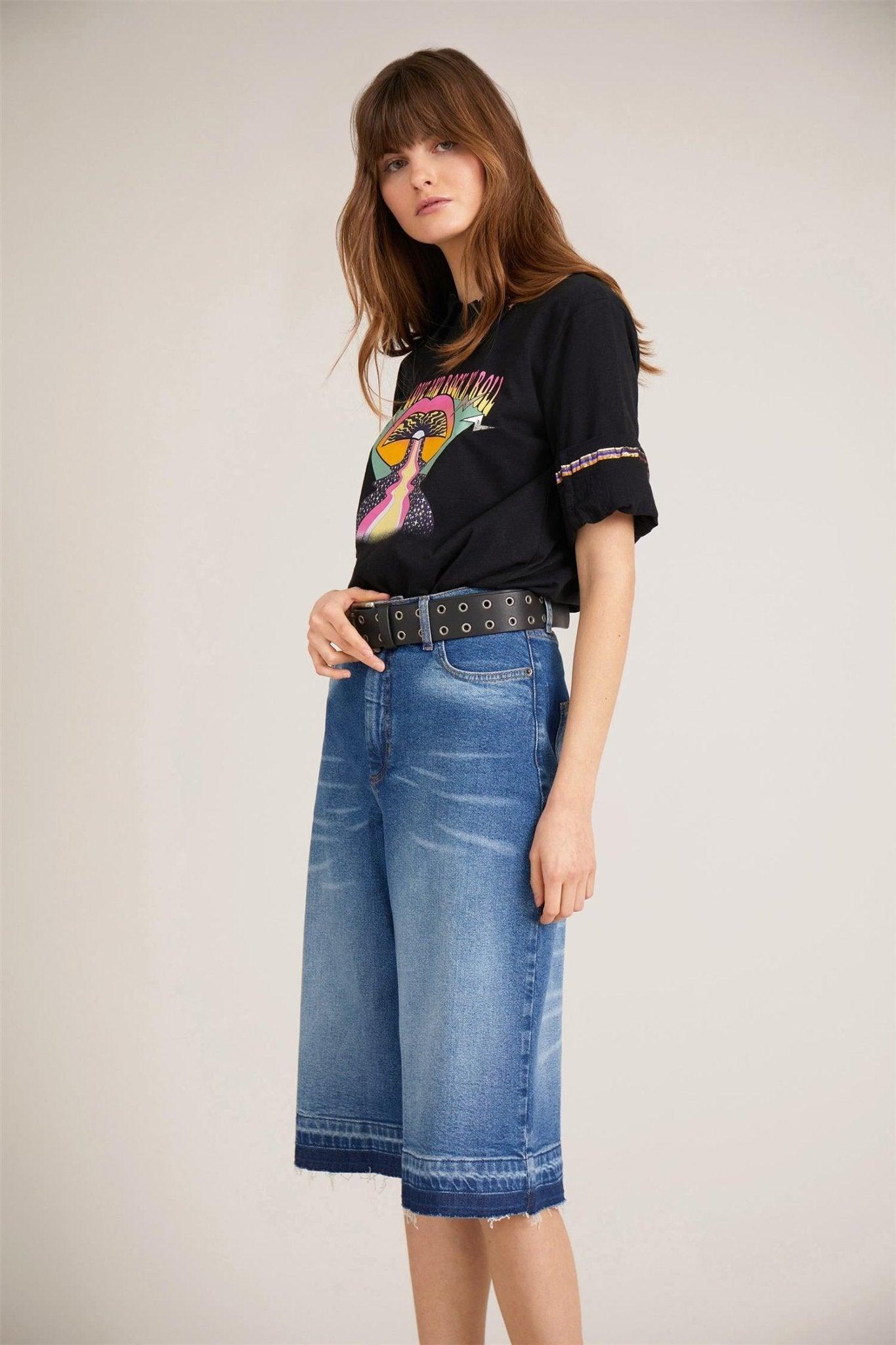 Dame med sort t-skjorte med fargerikt motiv og vide denim bermudashorts