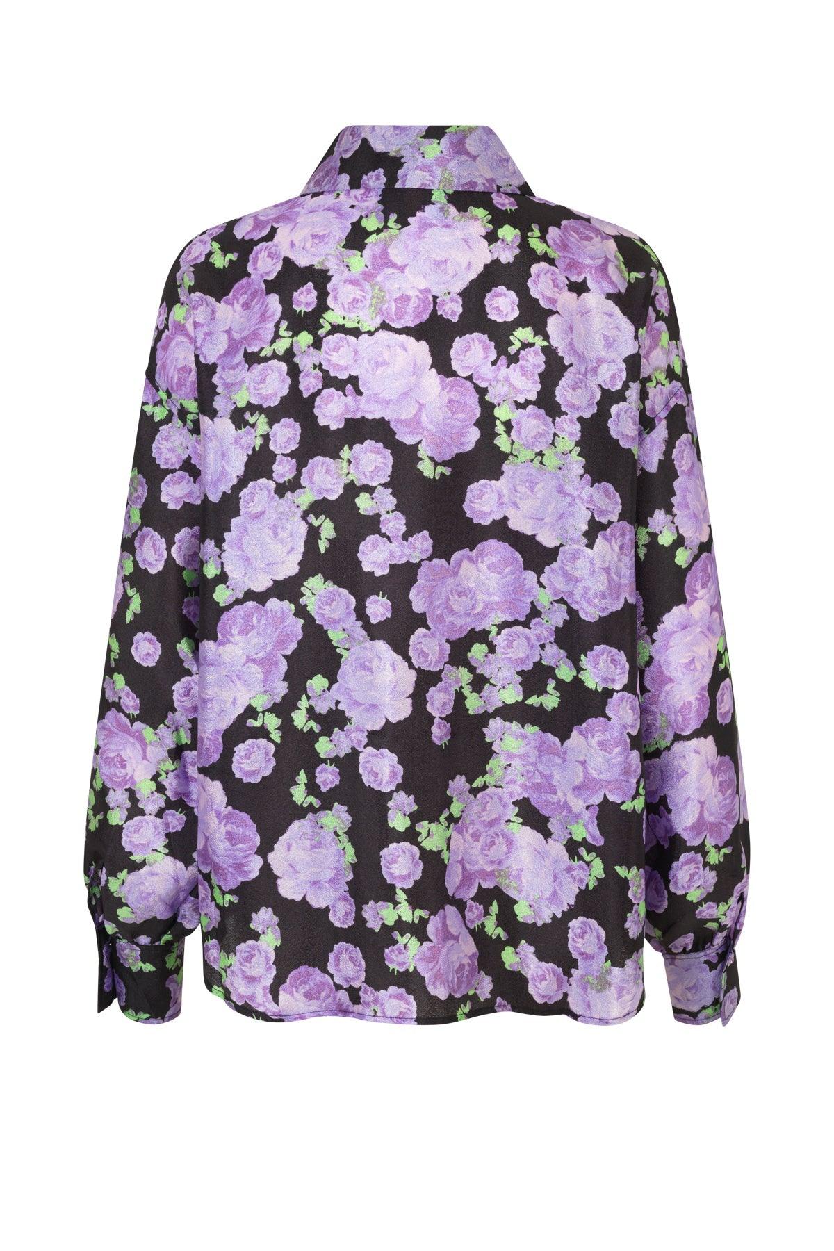 Lilla bluse med blomsterprint og lange ermer, sett bakfra mot hvit bakgrunn