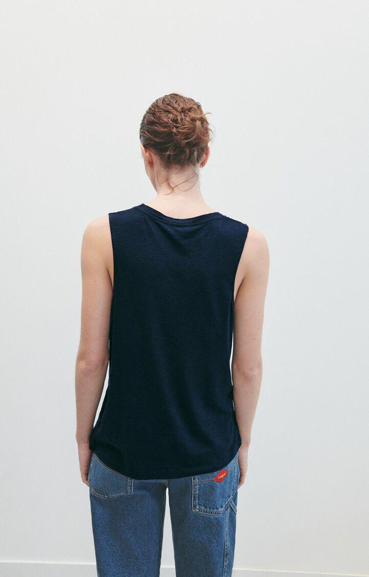 Dame i mørkeblå tank top og blå jeans, sett bakfra, mot lys bakgrunn.