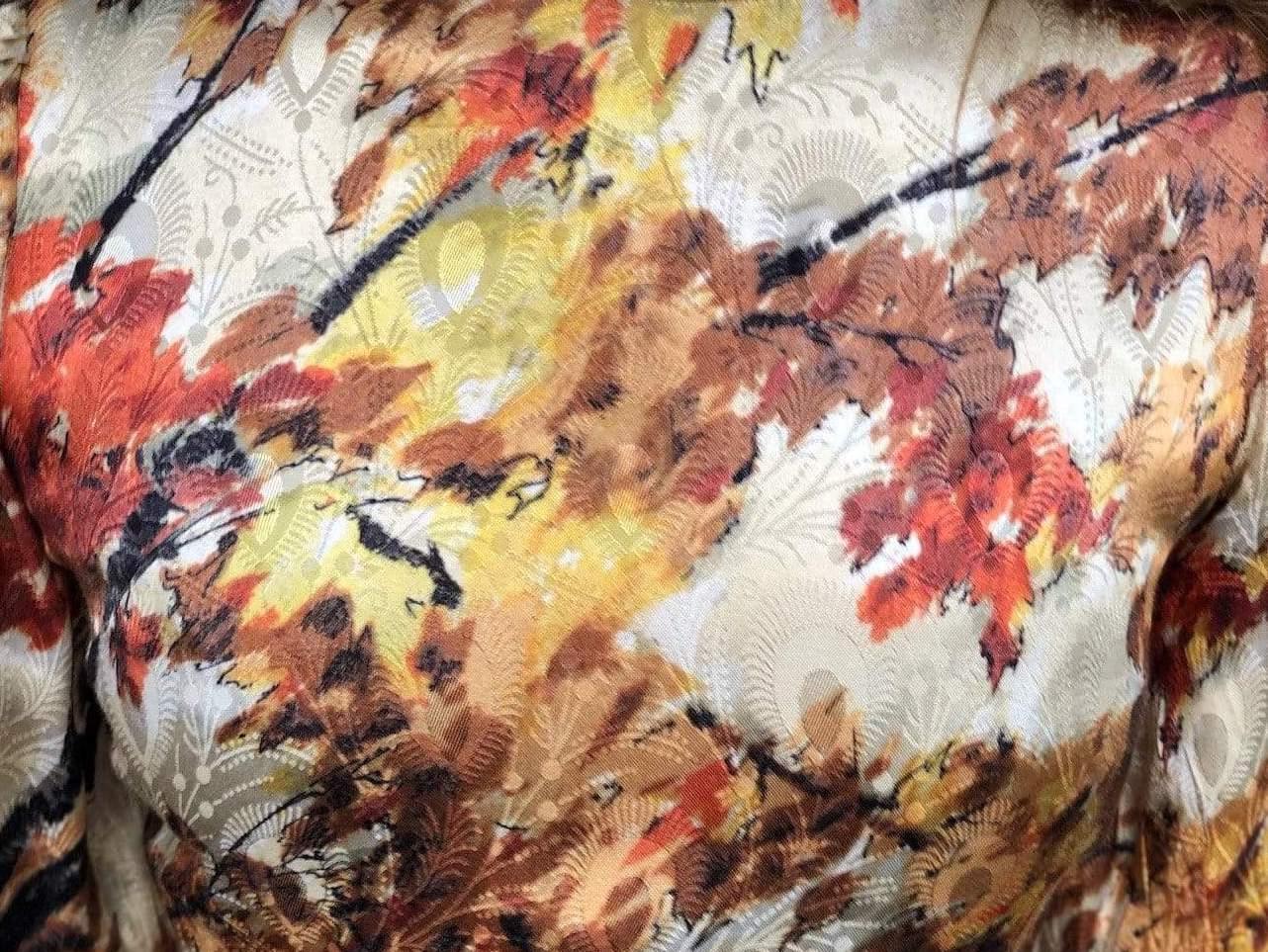 Nærbilde av jacquard midikjole med høstinspirert bladermønster i rødt, brunt og gult.