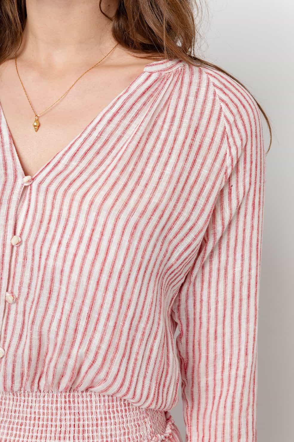 Nærbilde av dame i hvit og rosa stripete kjole med v-hals og knapper.