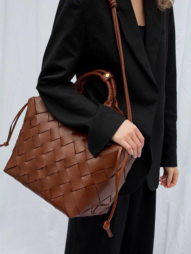 Dame i svart dress med stor flettet brun skinnveske, elegant tilbehør for kvinner