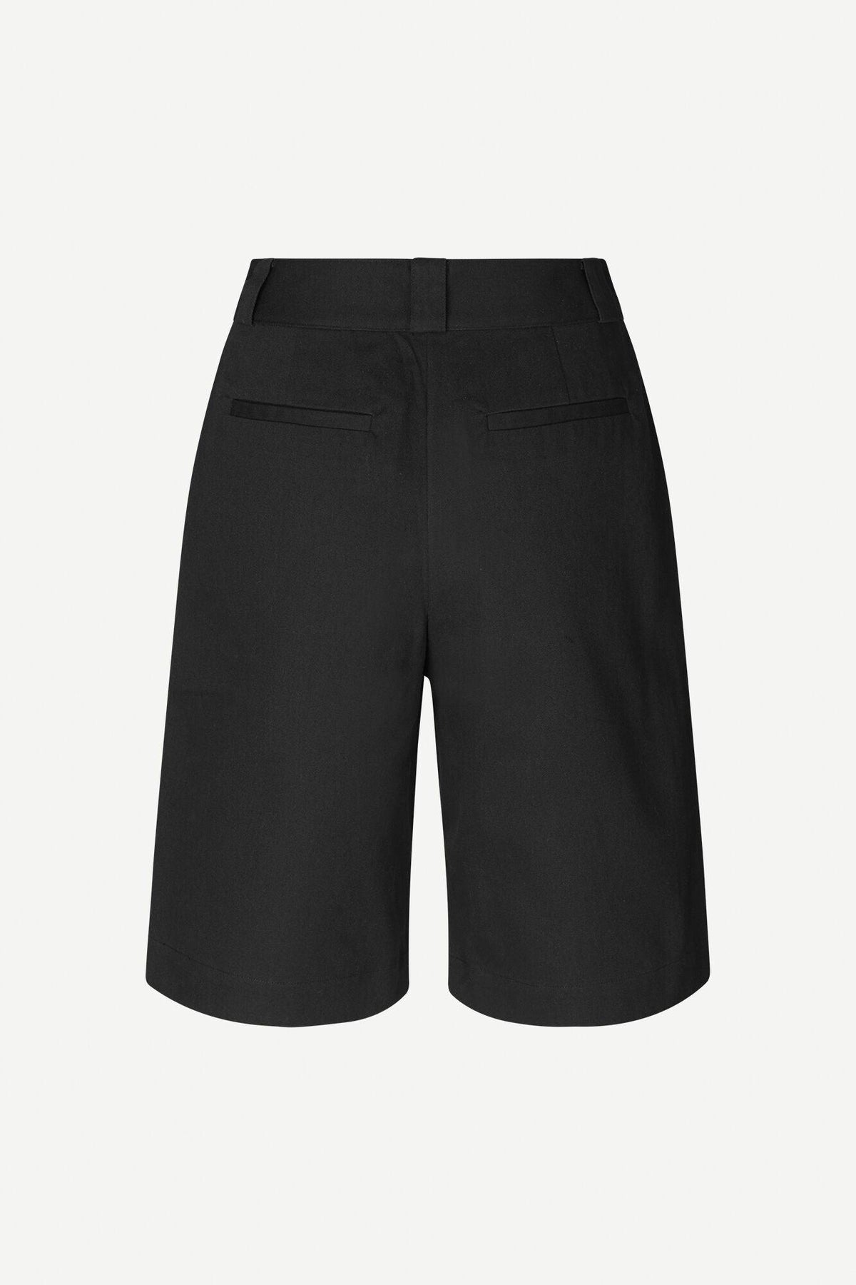 Bakside av klassiske svarte dame-shorts med passpolerte lommer og beltehemper.