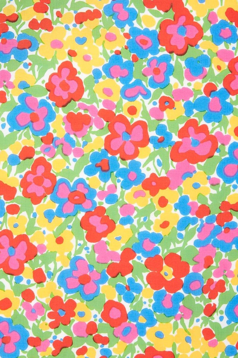 Fargerikt blomstrete stoff med røde, blå, gule og rosa blomster på grønn bakgrunn.