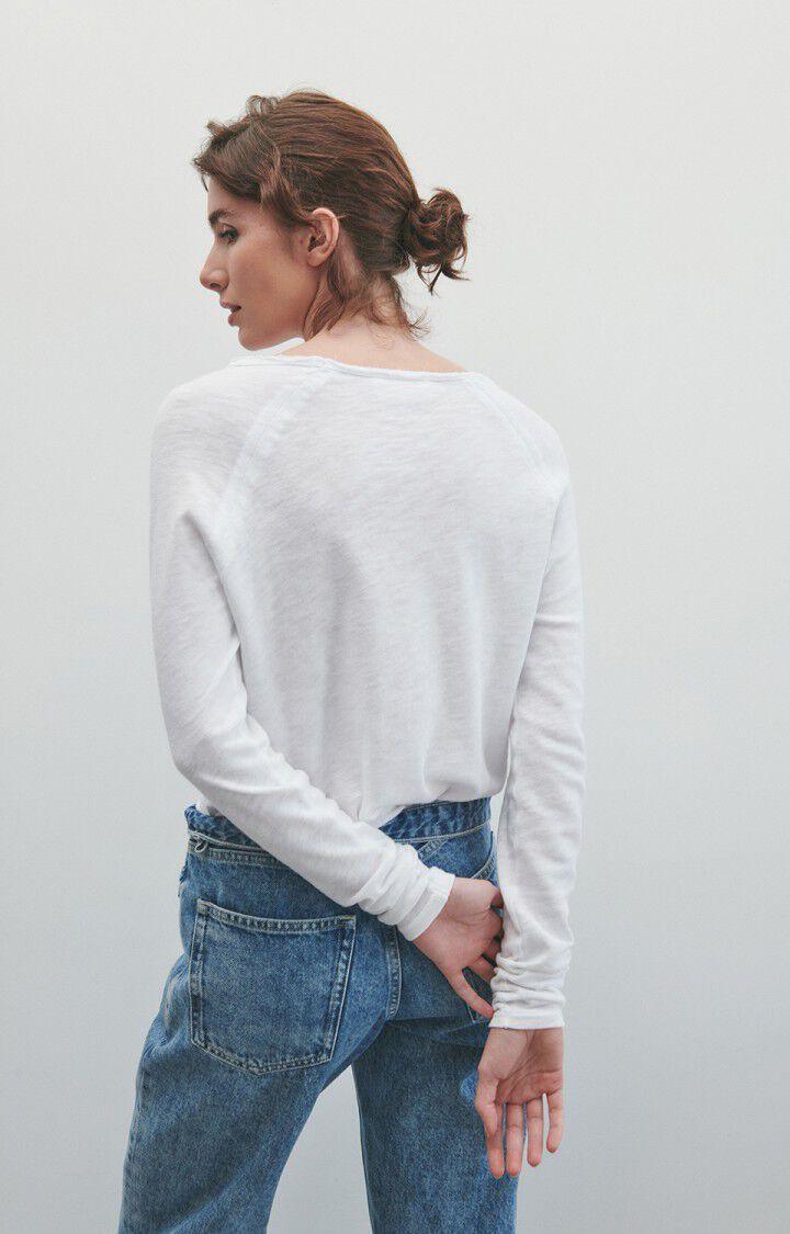 Dame med hvit langermet genser og blå jeans, sett bakfra mot lys bakgrunn