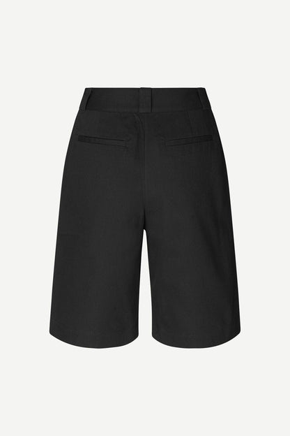 Bakside av klassiske svarte dame-shorts med passpolerte lommer og beltehemper.